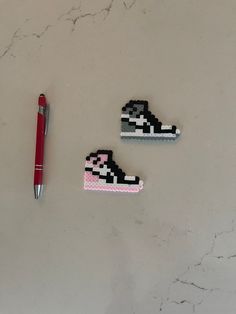 three pieces of art made to look like shoes with a pen on the table next to them