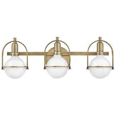 three light bathroom fixture in an antique brass finish with frosted glass balls on the sides