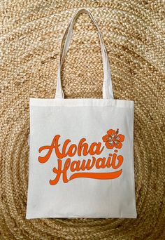 "This Aloha Hawaii tote bag is perfect to take with you on a tropical getaway or carry because you enjoy the island life.  Pack up your essentials and your ready to go on an adventure. This tote bag is made from 100% organic cotton and is available in six colors.  ---- DETAILS ---- 100% Organic Canvas Tote Bag  Font Vinyl Design  Measurements 15\" X 14\"  Handels 22\" Handle Drop 9\"  Thanks for shopping at Beach Babe Vibes Shop." Natural Canvas Travel Bag Suitable For Gifts, Natural Canvas Travel Bag, Tropical Bags For Everyday Beach Use, Tropical Style Beach Bag For Daily Use, White Tropical Bag For Everyday Use, Tropical Style Tote Beach Bag For Everyday Use, Tropical Style Tote Shoulder Bag For Vacation, Tropical Shoulder Bag For Beach Season Daily Use, Tropical Everyday Bags For Summer