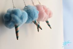 three different colored cotton balls are hanging from hooks on a white wall with chain attached to it