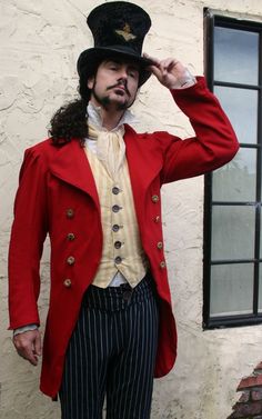 a man in a red jacket and top hat is posing for the camera with his hand on his head