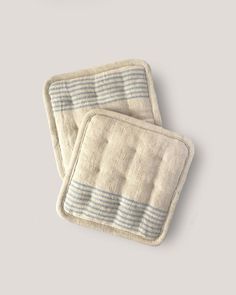 two white and blue striped dishcloths sitting on top of each other, one is folded