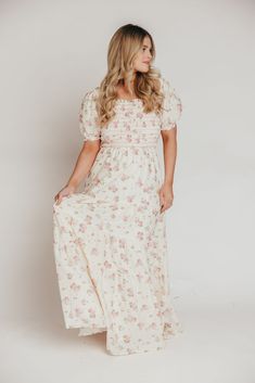 If you're looking ahead to blooming flowers and sunshine, you need this beautiful dress to help herald in springtime! This gem is crafted from a charming, 100% cotton floral print, and features a smocked bodice with sleeves that can be worn on or off the shoulders. It's a must-have for baby showers, gender reveals, or christenings! The Harper is sure to sell out, so don't wait to snag yours! FIT: Runs true to size. The bodice is stretchy and smocked, but the rest of the dress does not have stret Feminine Maxi Dress With Empire Waist For Garden Party, White Dresses With Floral Print And Empire Waist, Feminine Floral Embroidered Maxi Dress For Garden Party, Feminine Maxi Dress With Floral Embroidery For Garden Party, Spring Floral Print Maxi Dress With Empire Waist, Spring Bohemian Empire Waist Dress, Feminine Cream Floral Print Maxi Dress, Feminine Cream Maxi Dress With Floral Print, Beige Maxi Floral Dress For Spring