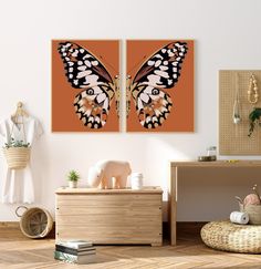 two butterfly paintings hang on the wall above a dresser in a room with wooden floors