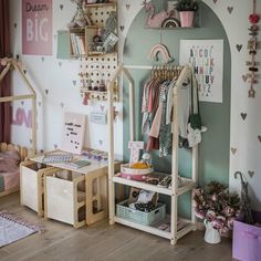 a child's room with lots of toys and decor on the walls, including clothes racks