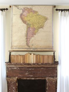 an old fireplace with books on it and a map hanging over the mantle in front of it