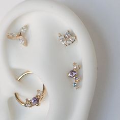 three different types of ear piercings sitting on top of a white object with gold accents