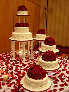 three tiered wedding cake with red roses on the table