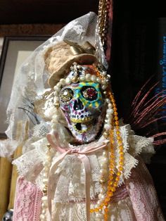 a doll is dressed in white and has beads on it's head, while wearing a veil