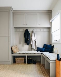 a white bench sitting under a window next to a coat rack