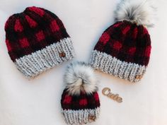 three knitted hats with pom - poms laying on top of each other