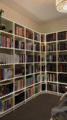 a book shelf filled with lots of books next to a lamp on top of a bed