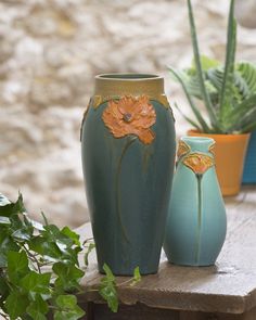 three vases with flowers painted on them are sitting on a table next to plants