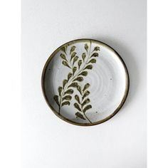 a white and gold plate with green leaves on the rim, against a white background