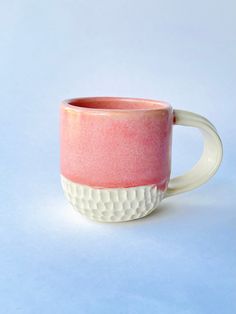 a pink and white coffee cup sitting on top of a table