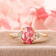 a pink diamond ring sitting on top of a table next to a bouquet of flowers