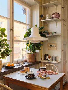 a small table with food on it in front of a window and potted plant