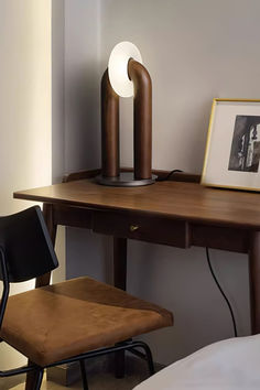 a desk with a lamp and chair next to it