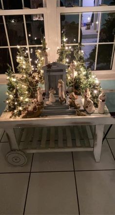 a white bench with christmas trees and lights on it in front of a large window