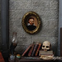 there is a skull on the table next to some books and a framed portrait in a gold frame