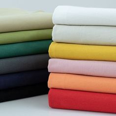 a stack of folded sheets sitting on top of each other in different colors and sizes