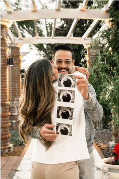 a man and woman kissing in front of an arch with pictures on the wall behind them