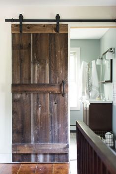 an open wooden door in the middle of a room with white walls and wood flooring