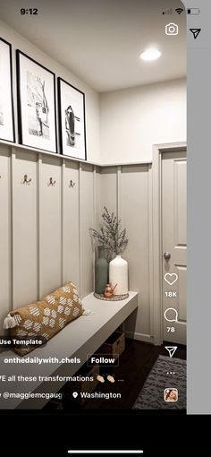 a white bench sitting next to a wall with pictures on it's sides and two vases filled with flowers