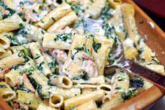 a wooden bowl filled with pasta and spinach