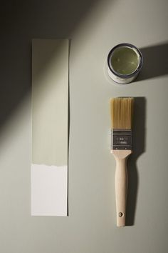 a paintbrush next to a white wall with a green tint on the side