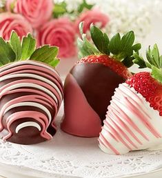 three chocolate covered strawberries sitting on top of a white plate next to pink roses