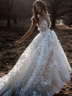 a woman in a white wedding dress is walking through the sand with her hand on her hip