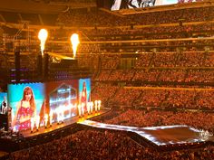 a large stadium filled with lots of people watching an event on big screens and lights