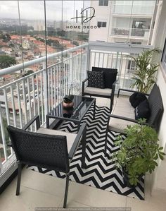 a balcony with black and white rugs, chairs and tables on top of it