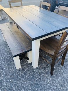 a table and bench made out of wood sitting on the ground next to some chairs