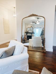 a living room filled with furniture and a large mirror on top of a wooden floor