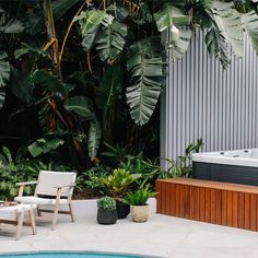 an outdoor hot tub next to a deck with chairs and potted plants on it