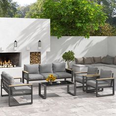 an outdoor living area with couches, chairs and fire place in front of a white stucco wall