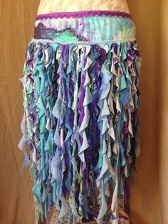 a woman's skirt made out of different colored fabrics and laces on a mannequin