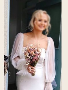 a woman in a white dress holding a bouquet of flowers