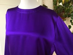 "Vintage 1980s-90's 100% silk satin blouse in a deep purple. Missing tags but is without a doubt 100% silk. Size is unknown but estimated to be a size S or possibly M. Please allow for extra room as blouse goes over the head. Single button at back of neck with keyhole closure, and matching buttons at cuffs. Boxy bodice with long sleeved that are puffed/gathered at cuffs. In AS IS condition; the silk has areas of \"stress\" or \"stretch mark\" type areas near armpits and at front, also has a fain Purple Silk Top For Formal Occasions, Formal Purple Silk Top, Purple Satin Party Top, Purple Silk Evening Blouse, Purple Silk Evening Top, Purple Silk Party Tops, 40s Hollywood, Secretary Office, Jewel Tone Dress