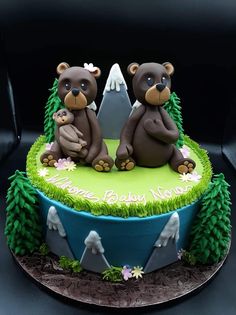 two teddy bears sitting on top of a green cake