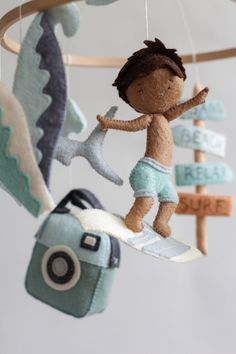 a stuffed animal hanging from a mobile with a boy on a surfboard in the air