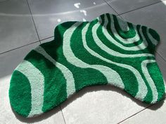 a green and white rug sitting on top of a floor next to a tile floor