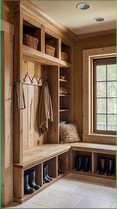 a wooden bench sitting under a window next to a pair of boots and coat racks