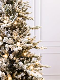 a white christmas tree with lights and snow on it