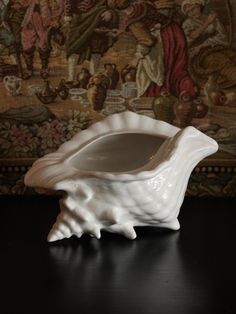 a white vase sitting on top of a table next to a wallpapered wall