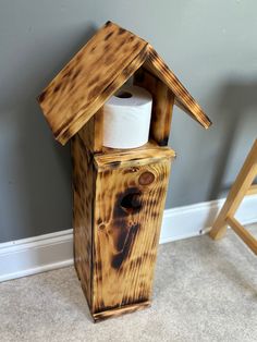 a toilet paper dispenser made out of wood with a roll of toilet paper in it