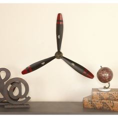 a clock made out of propeller blades sitting on top of a shelf next to a globe