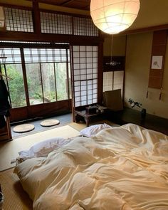 a large bed sitting in a bedroom next to a window covered in white sheets and pillows